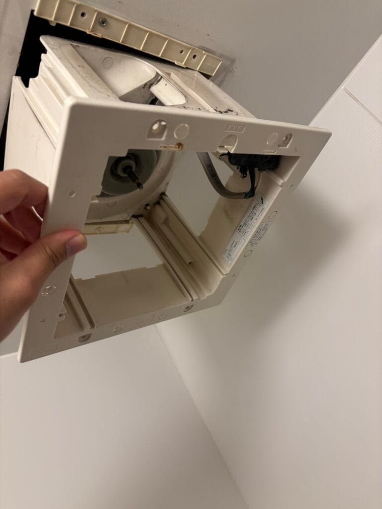 浴室の換気扇のパネルが外れた箇所を確認している写真